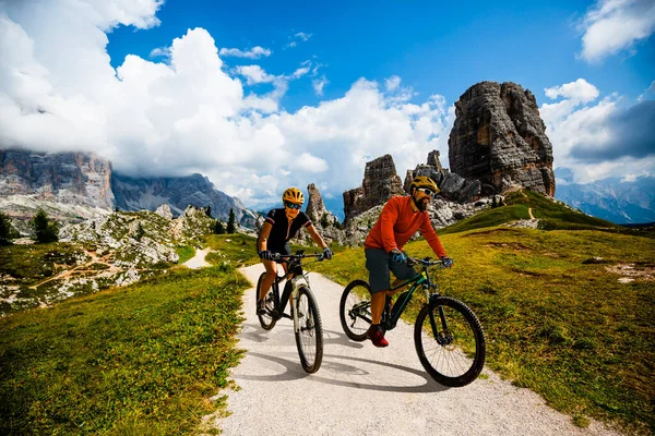 男性と女性はイタリアのドロミテで電動マウンテンバイクに乗っています 美しい山道でマウンテンバイクの冒険 — ストック写真