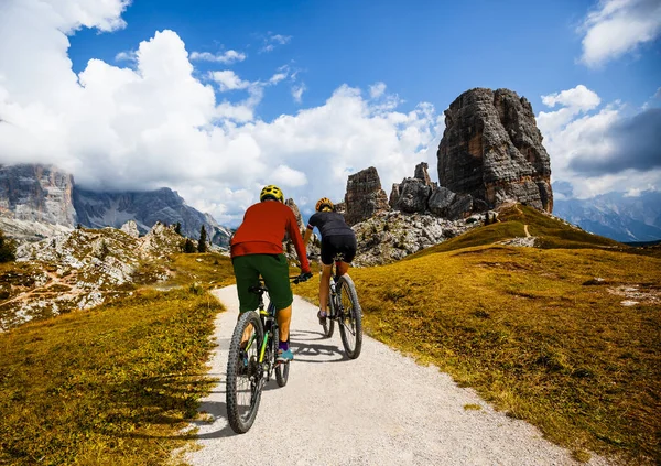 男性と女性はイタリアのドロミテで電動マウンテンバイクに乗っています 美しい山道でマウンテンバイクの冒険 ロイヤリティフリーのストック写真