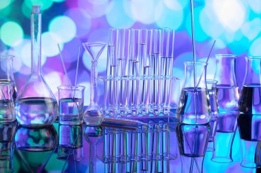 Covid 'e karşı test ve ilaç ile ilgili laboratuvar araştırmaları. Mavi bokeh arka planda cam tüpler ve beherler.