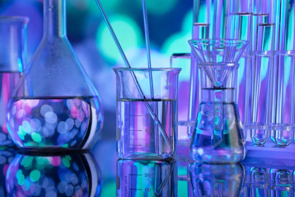 Covidに対するテストおよび薬に関する研究室調査 ガラス管とビーカー上の青いボケの背景 — ストック写真