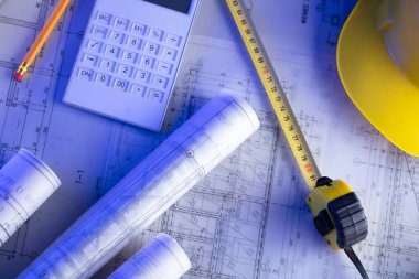 Müteahhit teması. Müteahhitin planları, defter ve alet çantası: sarı başlık, karalama, testere ve yarda..