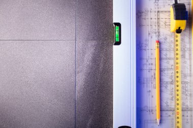 Müteahhit teması. Müteahhitin planları, defter ve alet çantası: sarı başlık, karalama, testere ve yarda..