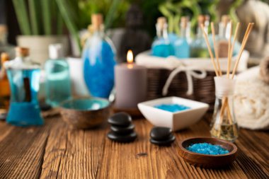 Spa and wellness concept. Bottles with bath and spa cosmetics, rolled up towels, bath salts and care products on wooden rustic paneling.