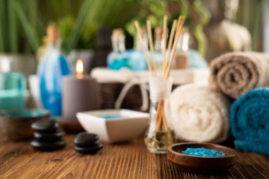 Spa and wellness concept. Bottles with bath and spa cosmetics, rolled up towels, bath salts and care products on wooden rustic paneling.