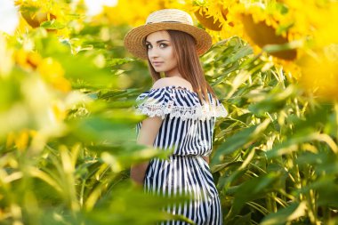 Gün batımında ayçiçeği alanında doğanın tadını çıkaran güzel kız.