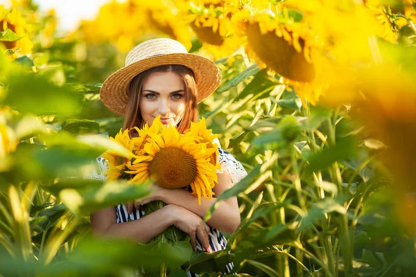 一个年轻的女人在盛开的向日葵地里抱着向日葵 — 图库照片