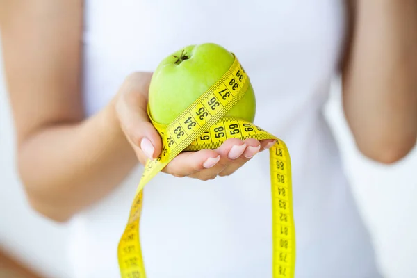 Close up woman holding apple with measuring tape.