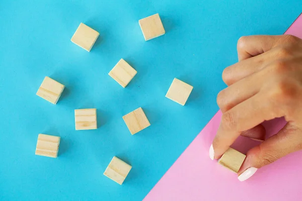 stock image Female hand arranging empty wood block and copy space on blue and pink background.