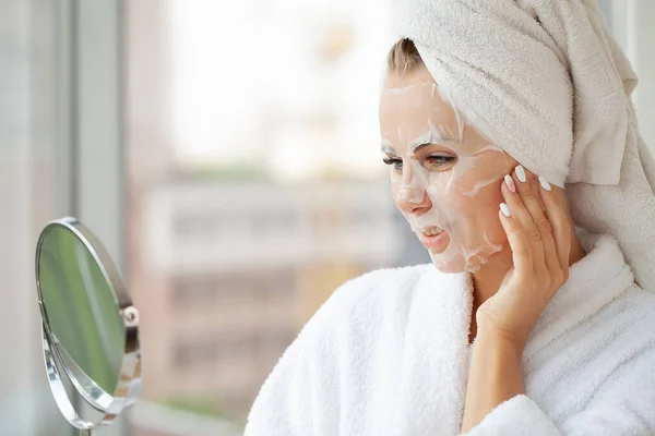 Junge Frau Entspannt Mit Einer Feuchtigkeitsspendenden Gesichtsmaske Aus Weißem Textil — Stockfoto