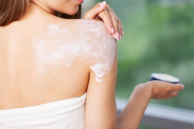 Mutlu kadın evde güzellik ürünleriyle rutin cilt bakımı yapıyor.