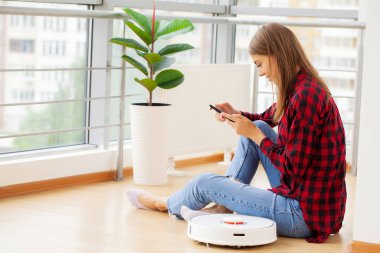 Genç kadın akıllı robot elektrik süpürgesini açıyor..