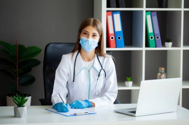 Koruyucu maskeli ve eldivenli kadın doktor hastanede..