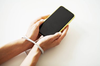 Erkek elleri zincirli ve akıllı telefonu tutuyor..
