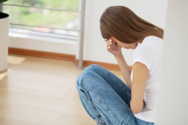 Güzel stresli genç bir ofis çalışanı ofiste acıdan başını tutup oturuyor..