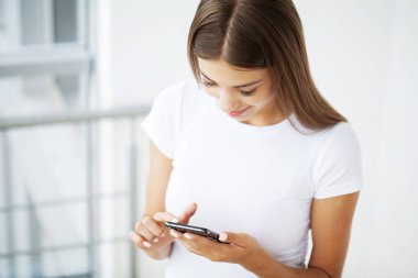 Kafasından vurulmuş genç bir kadın cep telefonu ekranına bakıyor..