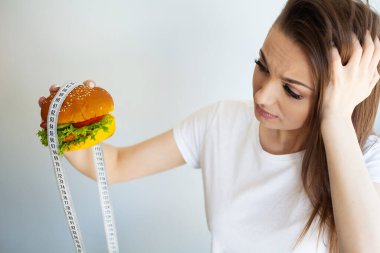 Diyet yaparken burgerli ve mezuralı bir kadın..