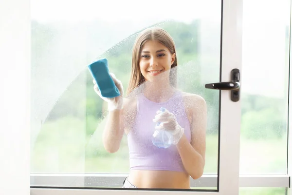 A hand in a rubber glove washes the window in the room.