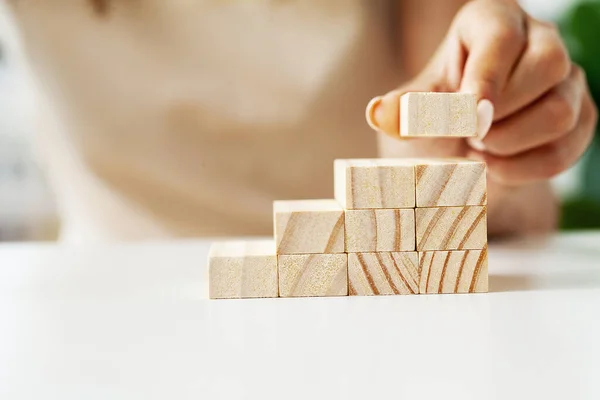 stock image Female hand arranging wood block stacking as step stair.