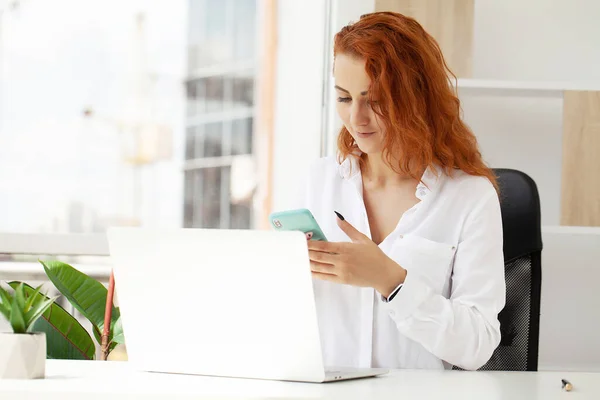 Rudowłosa Kobieta Rozmawiająca Przez Telefon Komórkowy Pracująca Zdalnie Laptopie — Zdjęcie stockowe
