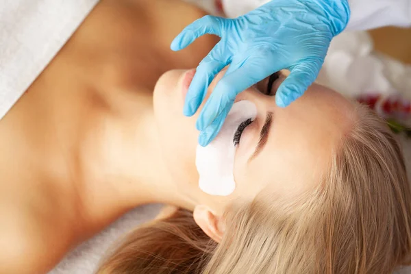 Young woman undergoing eyelash lamination in salon.