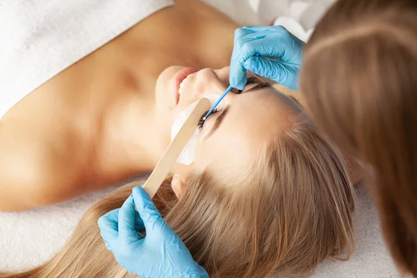 Young woman undergoing eyelash lamination in salon.