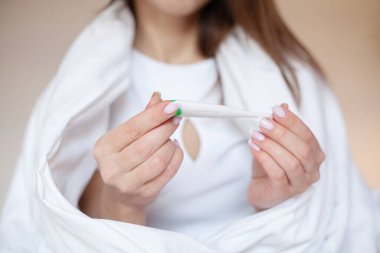 Dijital termometreyi tutan kadın ellerini kapat..