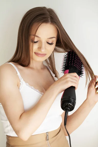 Happy young woman drying her hair with a hairdryer in the bathroom.
