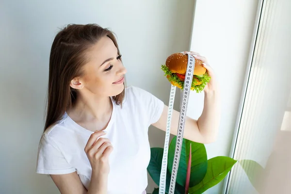 Kobieta Gospodarstwa Szkodliwe Tłuszczu Burger Taśmą Pomiarową — Zdjęcie stockowe
