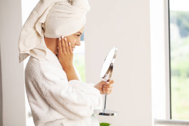 Güzel bir kadın yüzüne nemlendirici krem sürüyor.