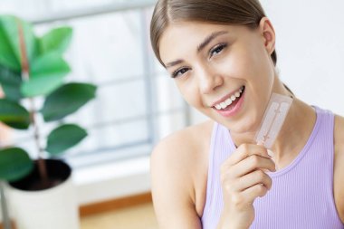 Beyaz dişleri olan, diş beyazlatmak için çizgili elleri olan güzel bir genç kız.