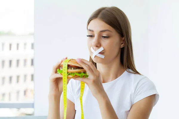 Ağzı Mühürlü Tatlı Bir Kadının Diyet Anlayışı Yağlı Hamburgeri Saklar — Stok fotoğraf