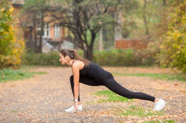 Genç bir kadın müzik dinlerken sokakta egzersiz yapıyor..