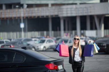 Güzel kız alışveriş çantalarını bagaja koyup gülümsüyor..