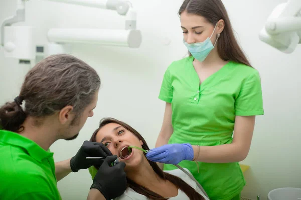専門医は彼女の歯を固定しながら 女性は医療センターで歯科椅子に座って — ストック写真