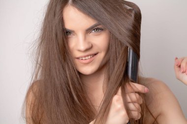 Güzel genç bir kadın sağlıklı ve parlak saçlarını tutuyor..