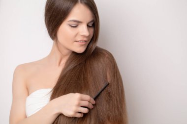 Güzel genç bir kadın sağlıklı ve parlak saçlarını tutuyor..