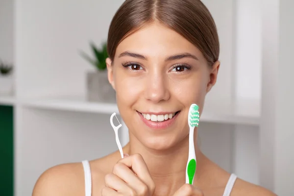 Stock image A young woman brushes her teeth with a toothpick and dental floss.