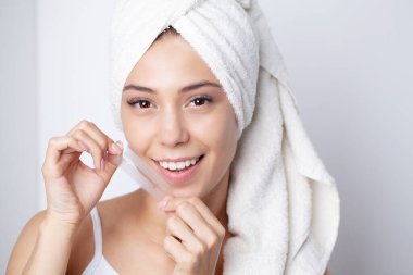 Dişleri beyazlatan, gülümseyen güzel kadın elinde beyaz şerit tutan.