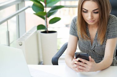 Sıkılmış genç kadın ofiste bilgisayar ekran bakarak ve bir dizüstü bilgisayar ile çalışma.