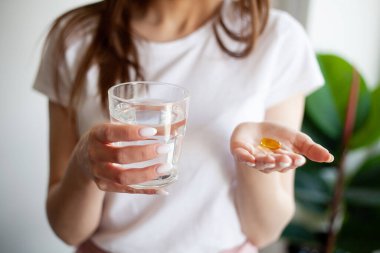 Balık yağı kaynaklı Omega-3 yağ asitli kapsülü tutan güzel bir kadın..