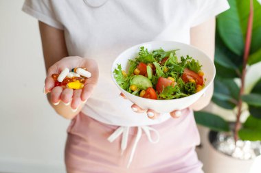 Genç bir kadın elinde beslenme takviyeleri olan bir sürü hap tutar..