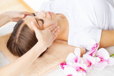 Kozmetik uzmanının elleri güzellik salonundaki kadına elle rahatlatıcı yüz masajı yapıyor..