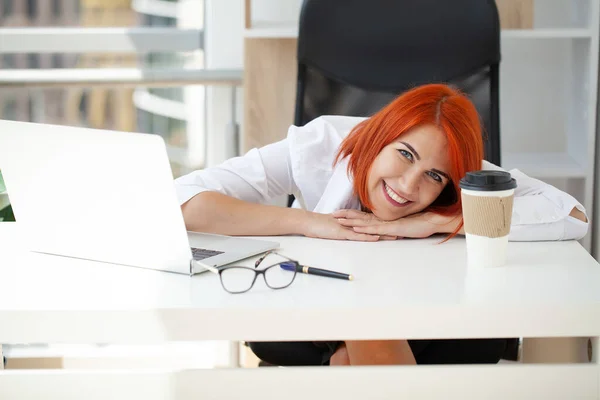 若い幸せな赤毛のビジネス女性はラップトップコンピュータを使用してオフィス内に座っています — ストック写真