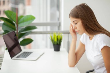 Şakaklara masaj yapan, bilgisayardan sonra baş ağrısı çeken bir kadın..