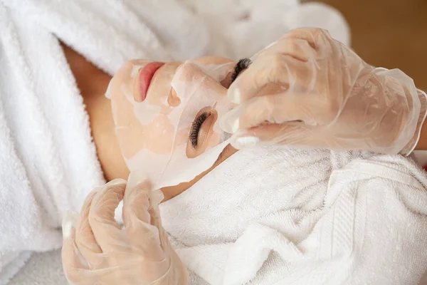 Kosmetologis Menerapkan Lembar Topeng Pada Wanita Spa Salon Kecantikan — Stok Foto