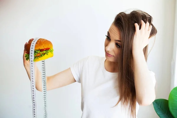 Kobieta Trzyma Niezdrowe Burger Taśma Miara Koncepcja Odchudzania — Zdjęcie stockowe