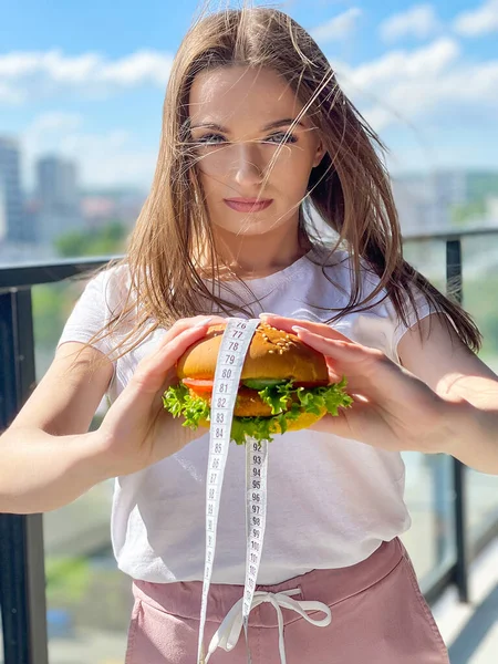 Kobieta Trzyma Niezdrowe Burger Taśma Miara Koncepcja Odchudzania — Zdjęcie stockowe
