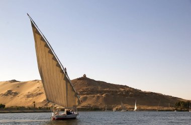 Aswan, Mısır 08 03 2022: Aswan, Mısır 'da Nil boyunca arka planda fil adası olan Feluccas. Felucca, tek yelkenli geleneksel bir ahşap yelkenli teknesidir.