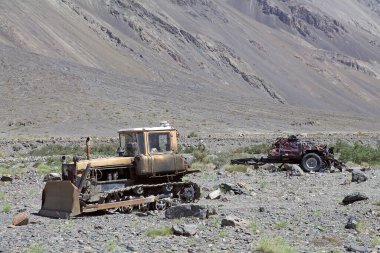 Tacikistan 'daki Gorno-Badakhshan' daki Bartang Vadisi boyunca nehir yatağındaki bir arabanın buldozer ve enkazı. Badakhshan, Tacikistan 'ın doğusunda, Pamir Dağları' nda özerk bir bölgedir.