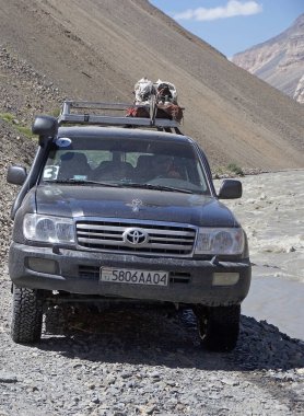 Off-road vehicles travel along the track swallowed up by the river along the Bartang Valley in the Gorno-Badakhshan in Tajikistan. The Badakhshan is in eastern Tajikistan, among the Pamir Mountains clipart